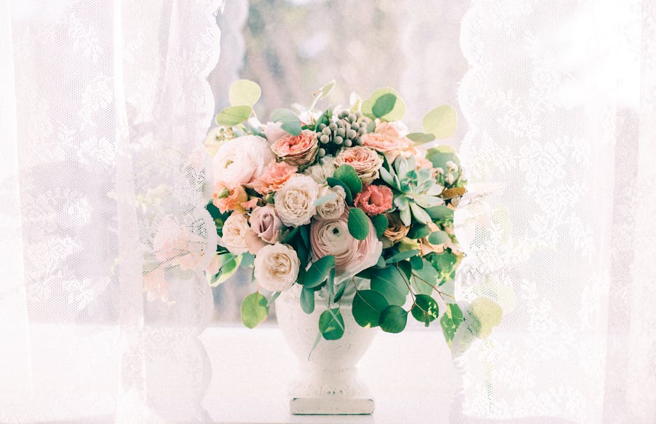 Close-up of a bridal bouquet held by a bride and groom during their wedding, featuring soft pink roses, white peonies, and mixed greenery including eucalyptus and sprigs with small pink flowers, arran